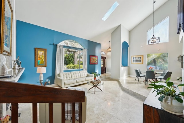 living area featuring baseboards, high vaulted ceiling, and a skylight