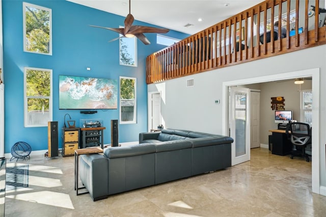 living room featuring visible vents, baseboards, ceiling fan, and a towering ceiling