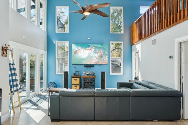 living area featuring visible vents, a high ceiling, and ceiling fan