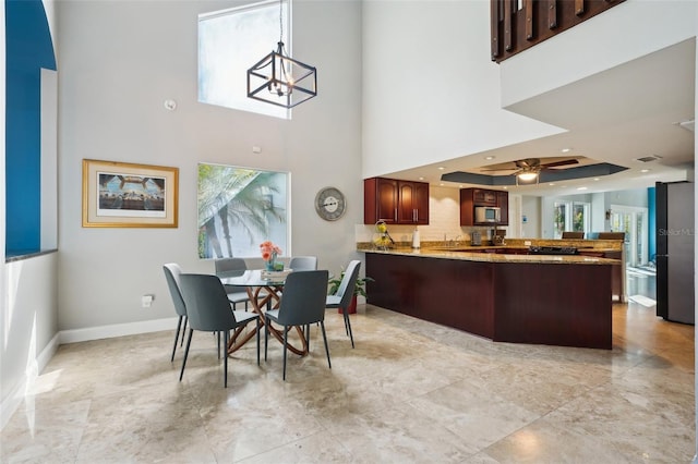 dining room featuring a tray ceiling, baseboards, a healthy amount of sunlight, and a towering ceiling