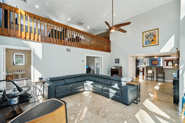 living area with visible vents, baseboards, a high ceiling, and a ceiling fan