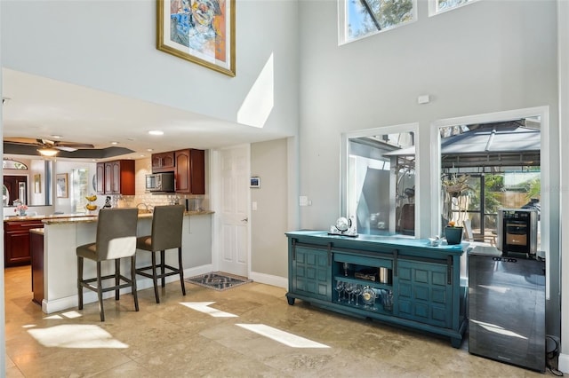 living area with baseboards, a high ceiling, and a ceiling fan