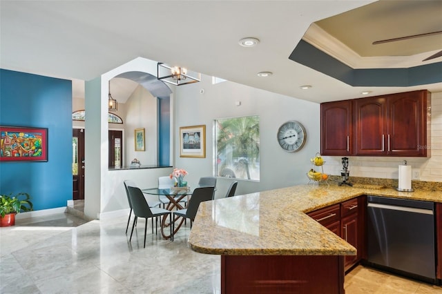 kitchen with a peninsula, light stone countertops, a raised ceiling, and stainless steel dishwasher