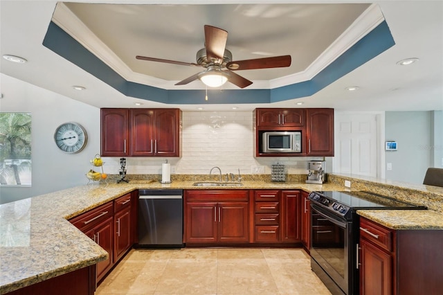 kitchen with a peninsula, a tray ceiling, appliances with stainless steel finishes, and a sink