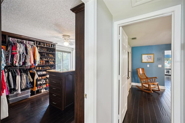 spacious closet with a ceiling fan, dark wood-style floors, and visible vents