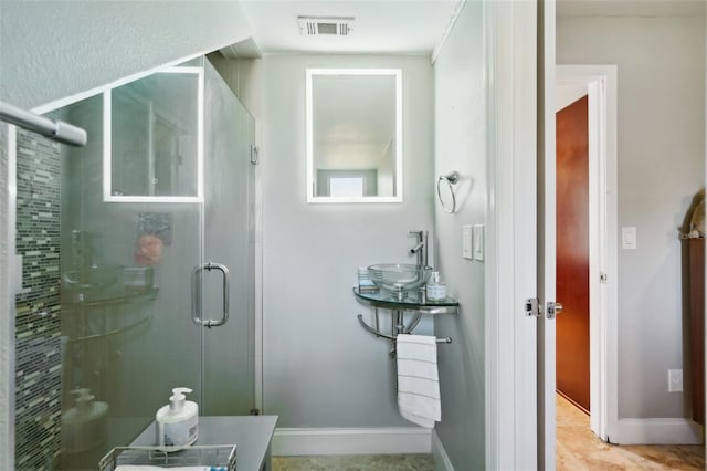 full bathroom with visible vents, a shower stall, baseboards, and a sink