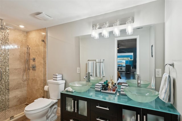 bathroom featuring double vanity, visible vents, a tile shower, and a sink