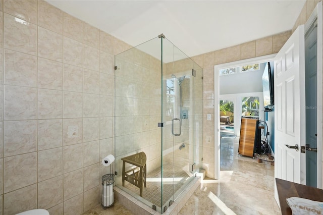 bathroom with a shower stall and tile walls