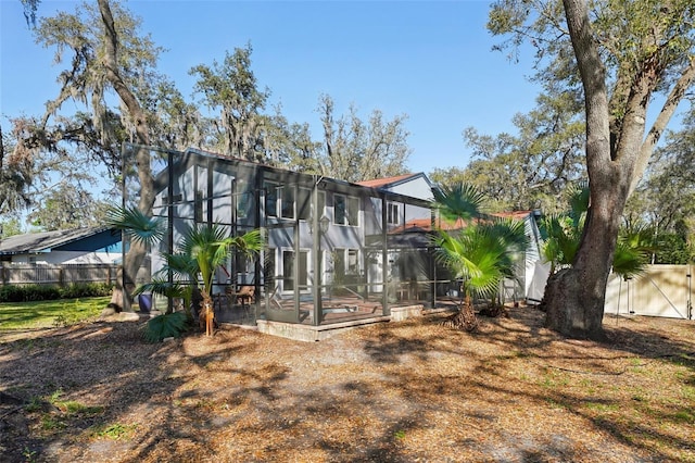 rear view of property with a lanai and fence