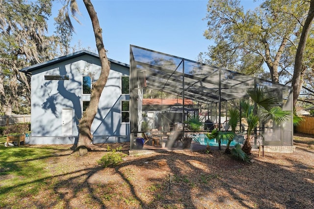 rear view of house with a fenced in pool, a lanai, and fence