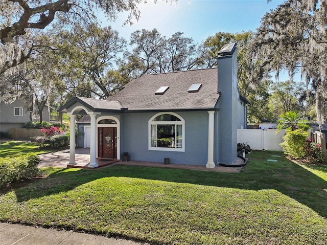 view of front of property with a shingled roof, a front yard, fence, and stucco siding