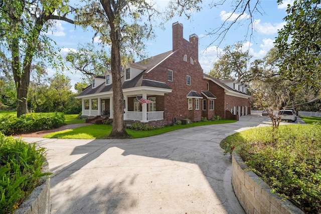 view of home's exterior featuring driveway, a chimney, a garage, a lawn, and brick siding