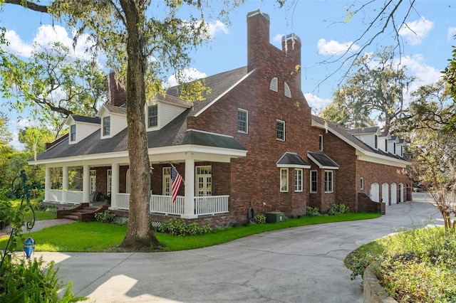 view of front of house with a front yard, driveway, a porch, a chimney, and brick siding