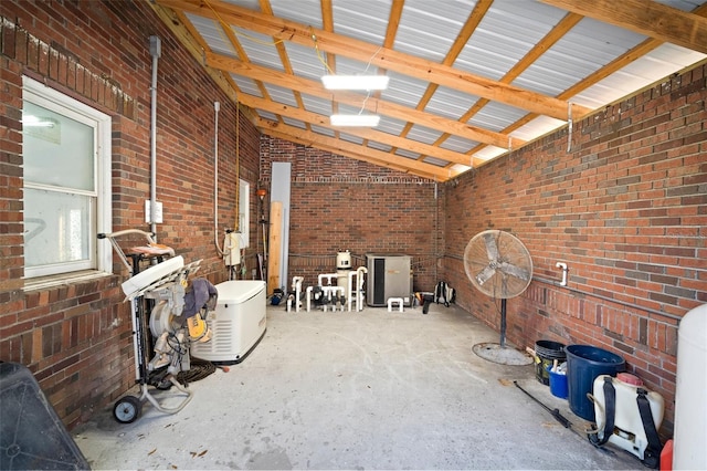 miscellaneous room with lofted ceiling, concrete flooring, and brick wall