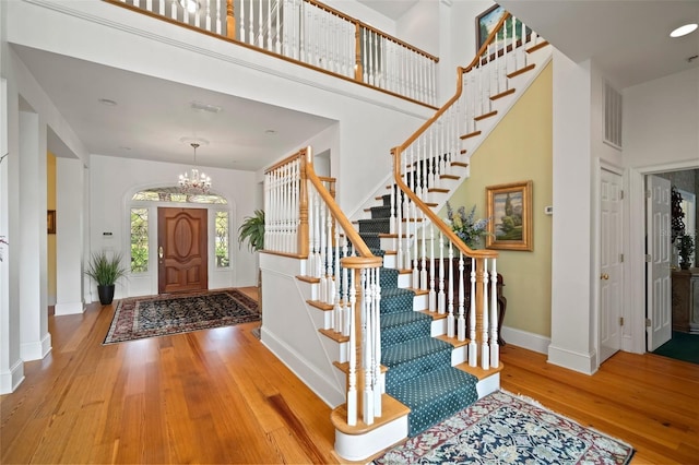 foyer entrance with a high ceiling, visible vents, baseboards, and wood-type flooring