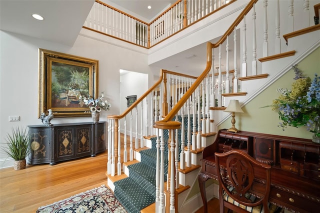 stairs featuring a towering ceiling, recessed lighting, baseboards, and wood finished floors