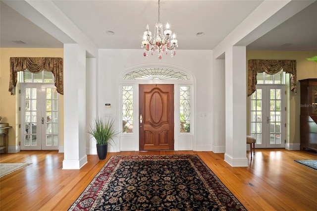 entryway with french doors, baseboards, wood finished floors, and a chandelier