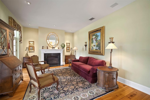 living area with visible vents, baseboards, a fireplace with flush hearth, recessed lighting, and wood finished floors