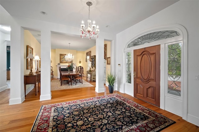 foyer entrance featuring baseboards, an inviting chandelier, and light wood finished floors