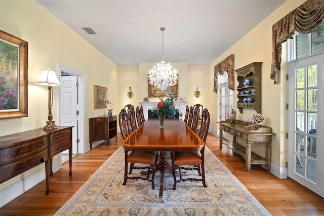 dining room featuring light wood-type flooring, visible vents, baseboards, and an inviting chandelier