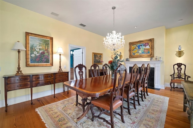 dining room featuring visible vents, baseboards, an inviting chandelier, and wood finished floors