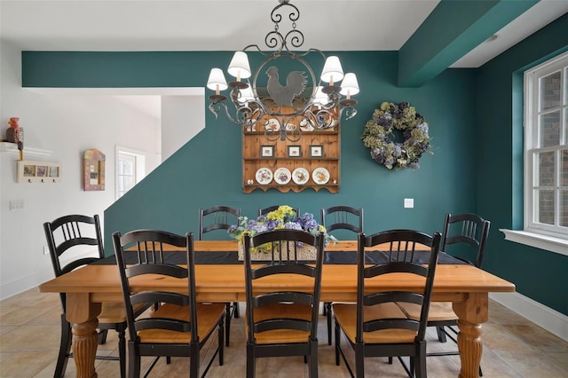 dining area with a wealth of natural light, light tile patterned floors, baseboards, and an inviting chandelier