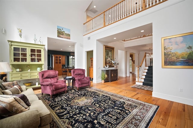 living area featuring an inviting chandelier, stairs, light wood-type flooring, and baseboards