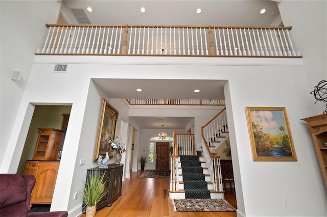 entryway with stairs, a high ceiling, wood finished floors, and a chandelier