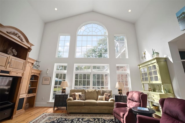 living room with light wood-style flooring, recessed lighting, and high vaulted ceiling