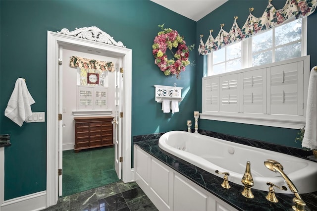 bathroom with marble finish floor, baseboards, and a garden tub