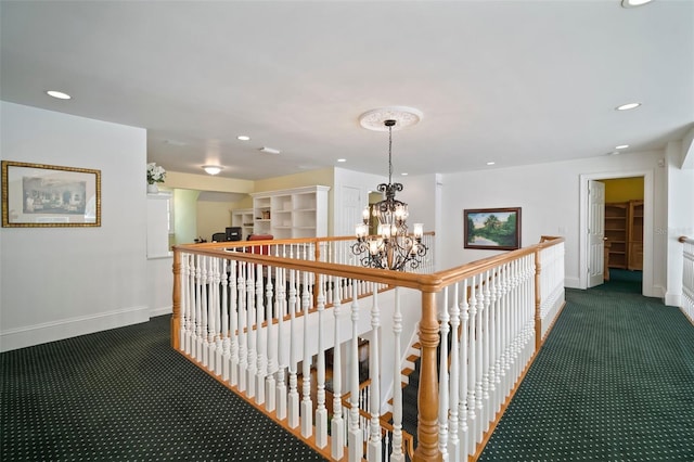 corridor with a notable chandelier, baseboards, and dark colored carpet