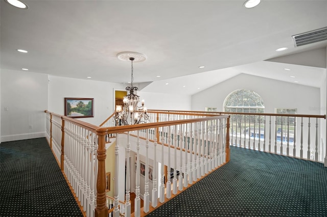 hall with visible vents, an inviting chandelier, lofted ceiling, and carpet