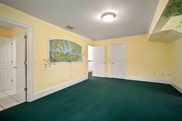 carpeted spare room featuring tile patterned floors, visible vents, and baseboards