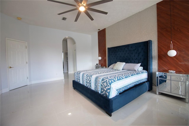 bedroom with visible vents, baseboards, arched walkways, ceiling fan, and tile patterned flooring