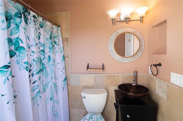 full bath featuring vanity, a shower with curtain, wainscoting, tile walls, and toilet