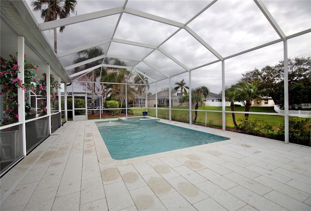 view of pool with a patio area, glass enclosure, a pool with connected hot tub, and a yard