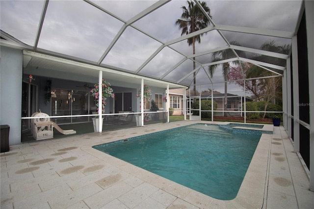 view of swimming pool with glass enclosure, a patio, a pool with connected hot tub, and ceiling fan