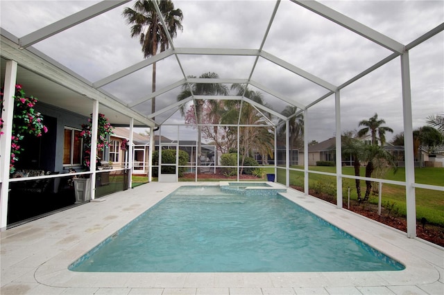 view of pool featuring a patio area, a lawn, a pool with connected hot tub, and glass enclosure