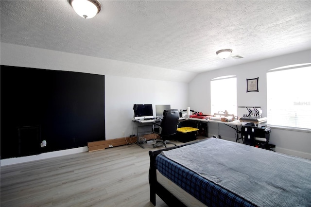 bedroom featuring visible vents, baseboards, lofted ceiling, and wood finished floors