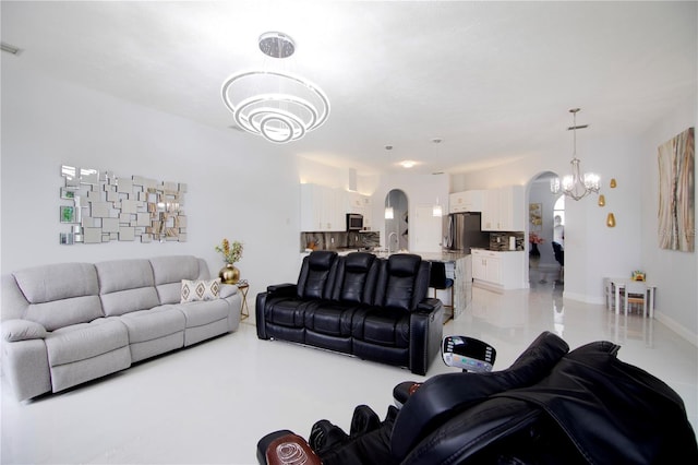 living area with visible vents, arched walkways, a notable chandelier, and baseboards