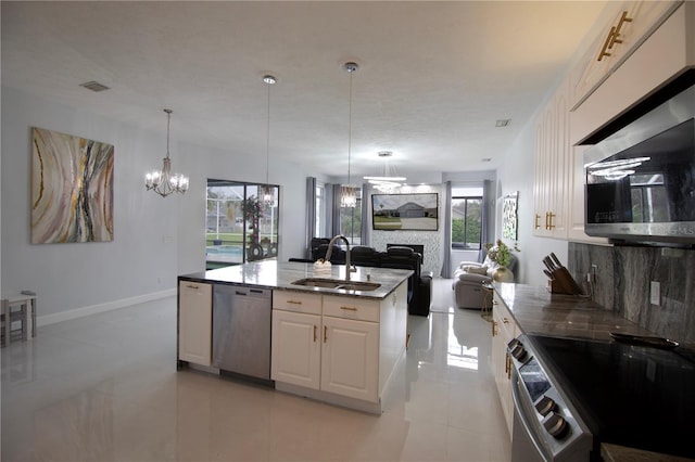 kitchen featuring open floor plan, stone counters, appliances with stainless steel finishes, white cabinets, and a sink