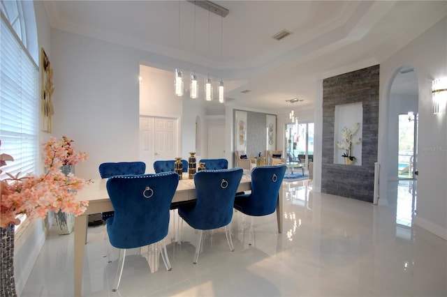 dining room with a tray ceiling, visible vents, arched walkways, and crown molding