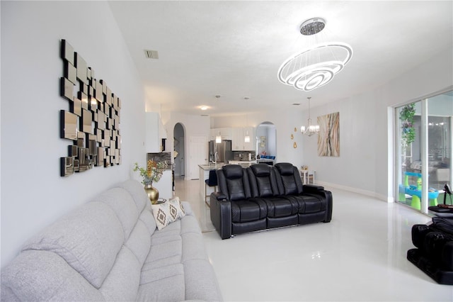 living area featuring baseboards, visible vents, arched walkways, and an inviting chandelier