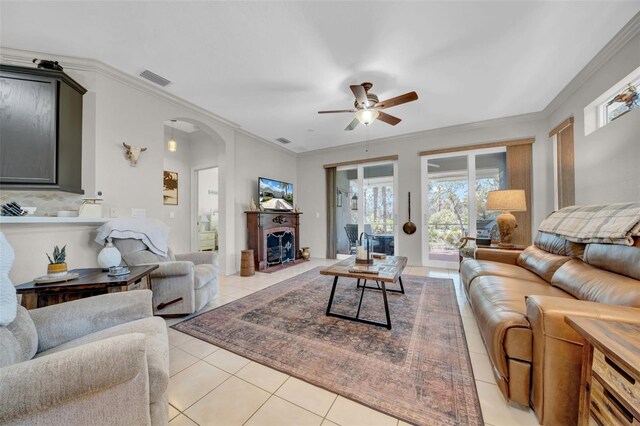 living area with visible vents, crown molding, arched walkways, a fireplace, and light tile patterned flooring