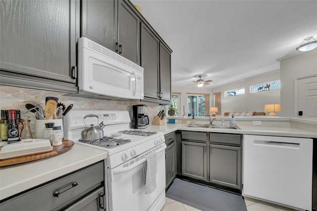 kitchen featuring decorative backsplash, white appliances, gray cabinetry, and a sink