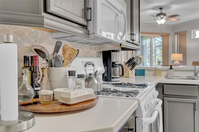 kitchen with white microwave, gray cabinets, ceiling fan, a sink, and light countertops