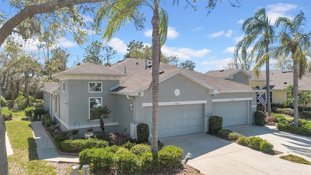 view of front facade featuring a shingled roof, concrete driveway, a garage, and stucco siding