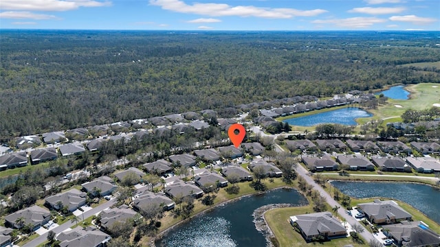 drone / aerial view with a view of trees, a water view, and a residential view