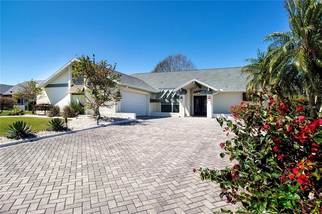 view of front of home featuring stucco siding, a shingled roof, decorative driveway, and a garage