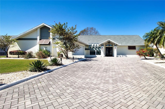 view of front of property with stucco siding, an attached garage, and decorative driveway